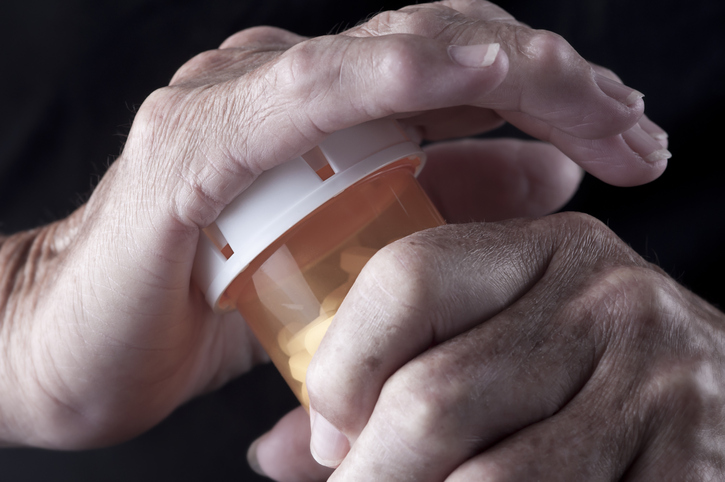 arthritic hands opening a pill bottle
