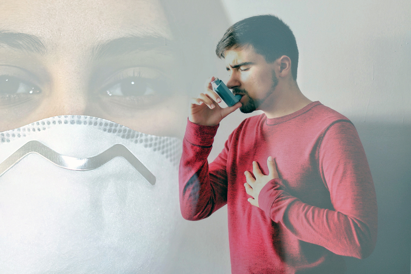 man using asthma inhaler against background of mask - signifying coronavirus
