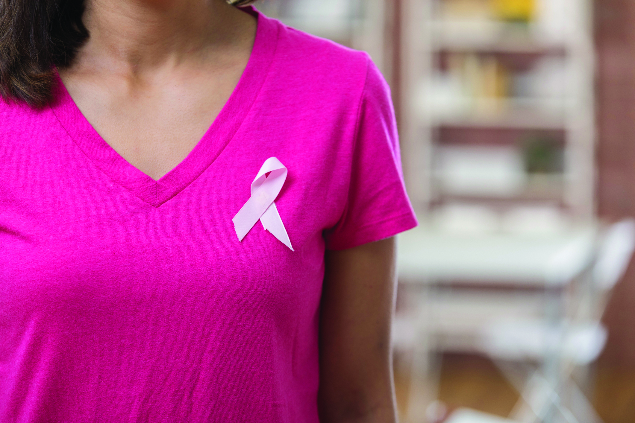 Woman in pink t-shirt with pink ribbon, denoting breast cancer