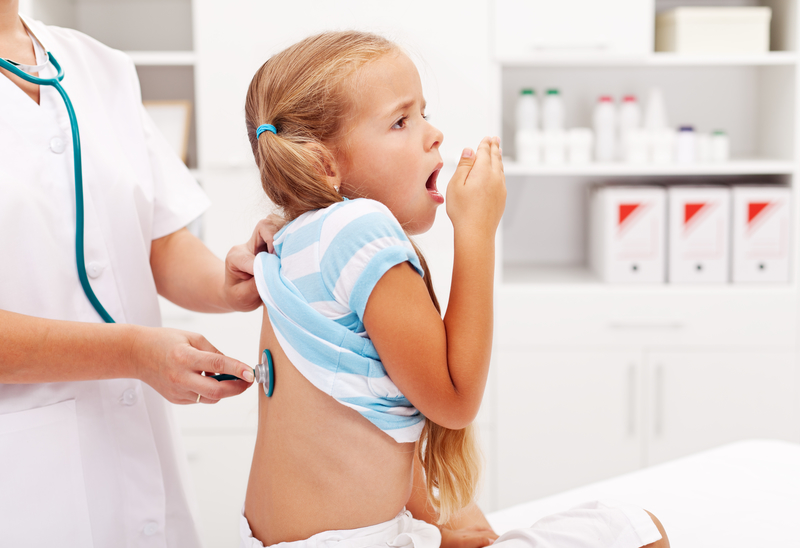 little girl coughing while doctor listens to her chest