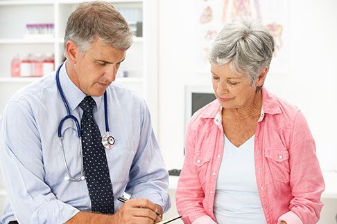 Male doctor talking to mature female patient