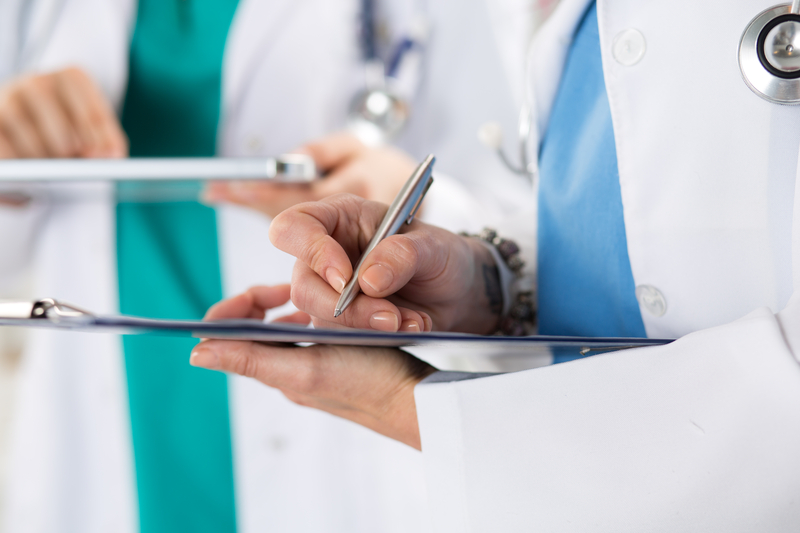 doctors recording information on clipboard and tablet
