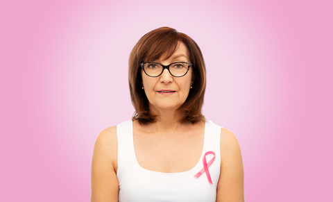 postmenopausal woman against pink background wearing ribbon