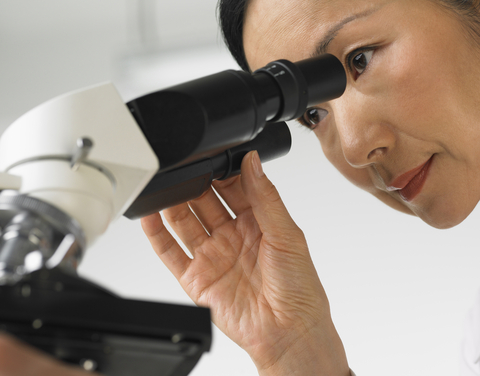 female pathologist looking down microscope