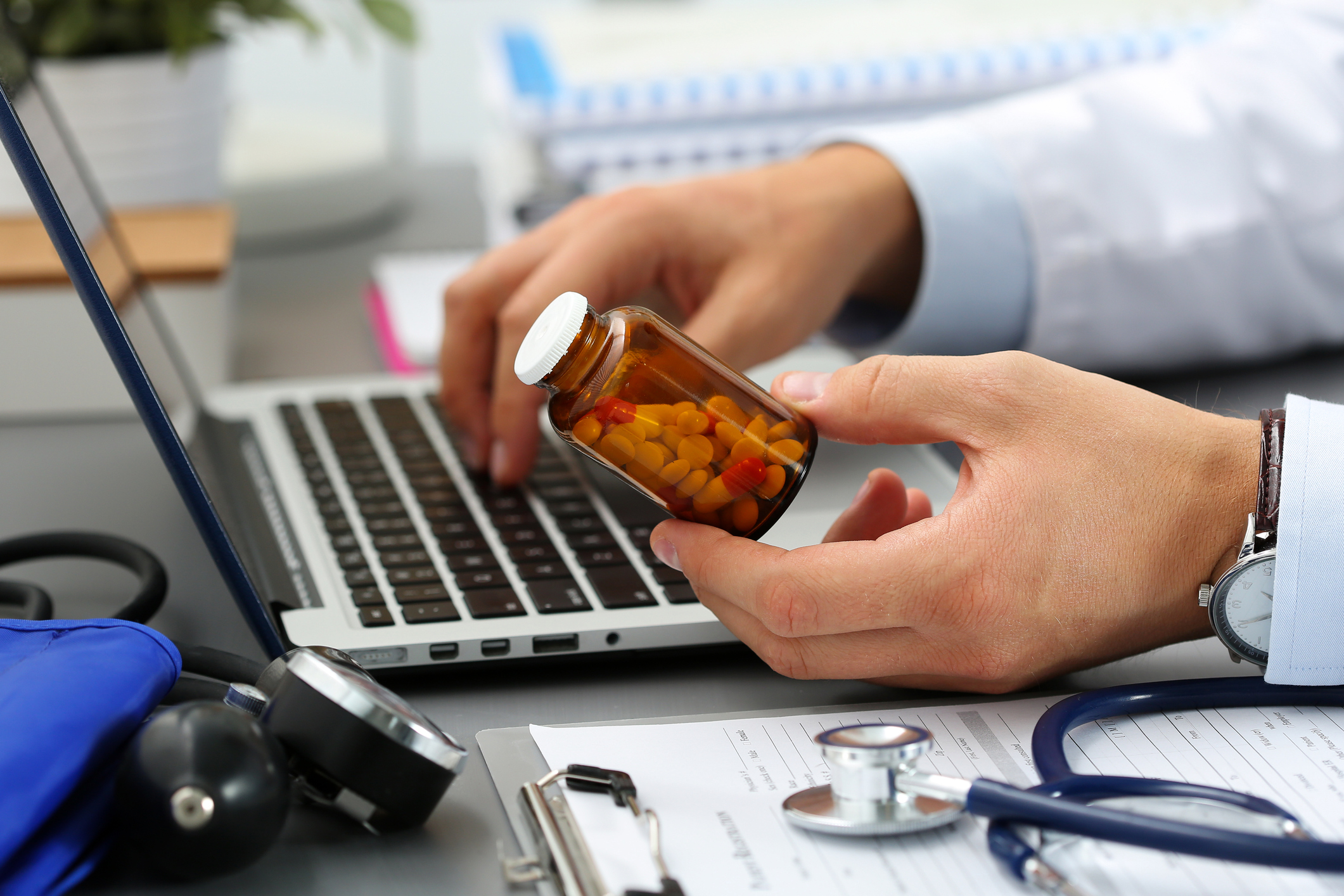 doctor looking up label on pill bottle on his computer