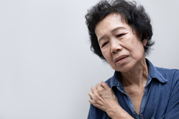 Senior Asian woman holding painful shoulder