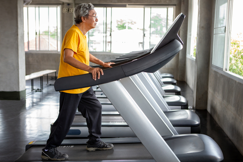 Older Asian man walking on treadmill