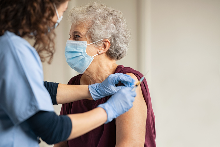 senior woman wearing mask having vaccination
