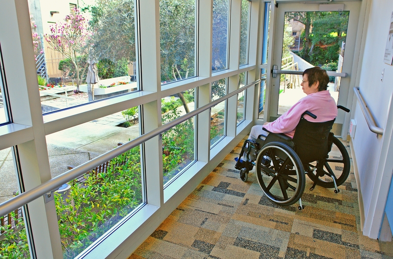 Woman in wheelchair happy looking out of window at garden