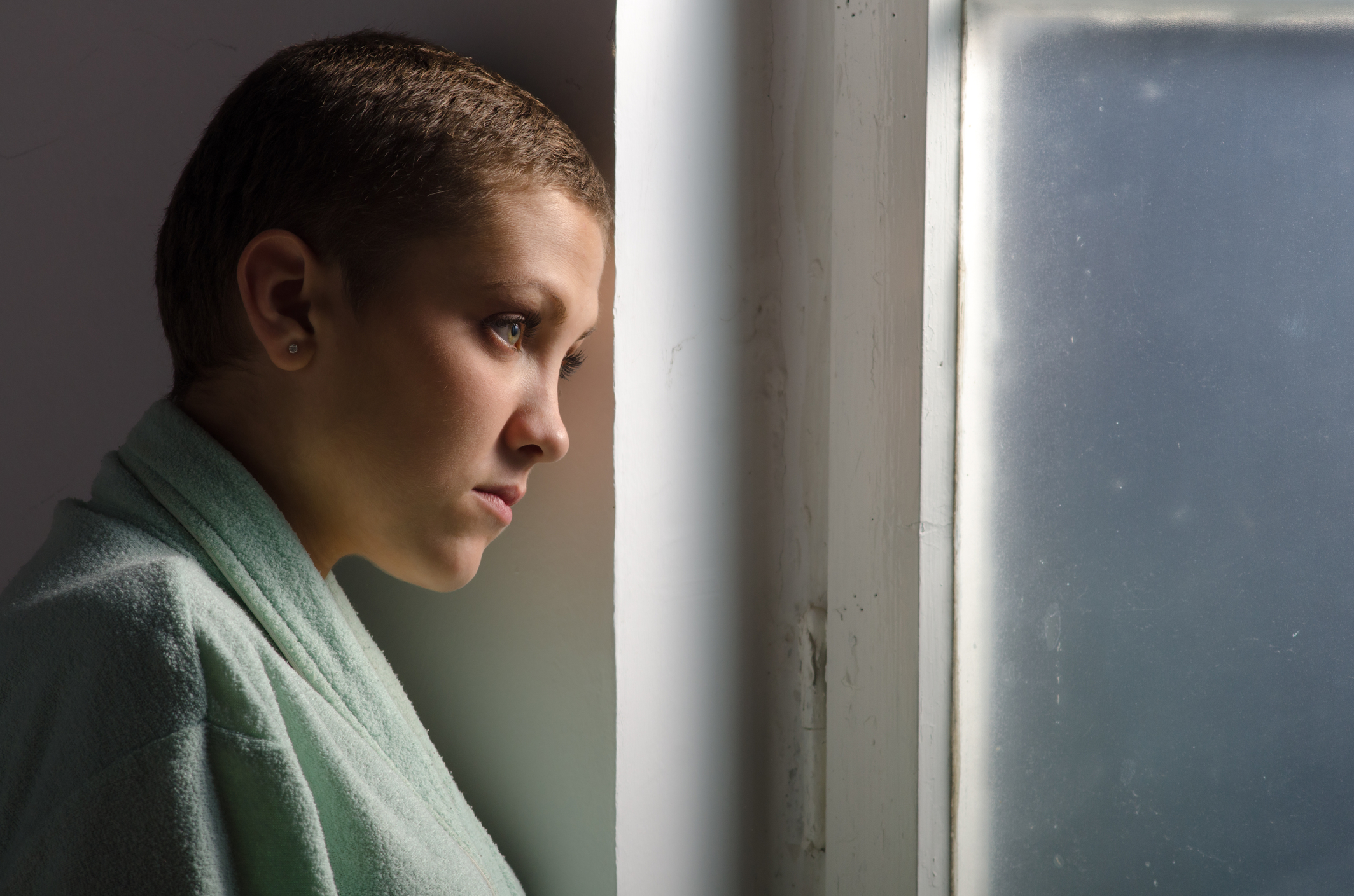 Young woman with shaven hair - cancer patient - looking sad
